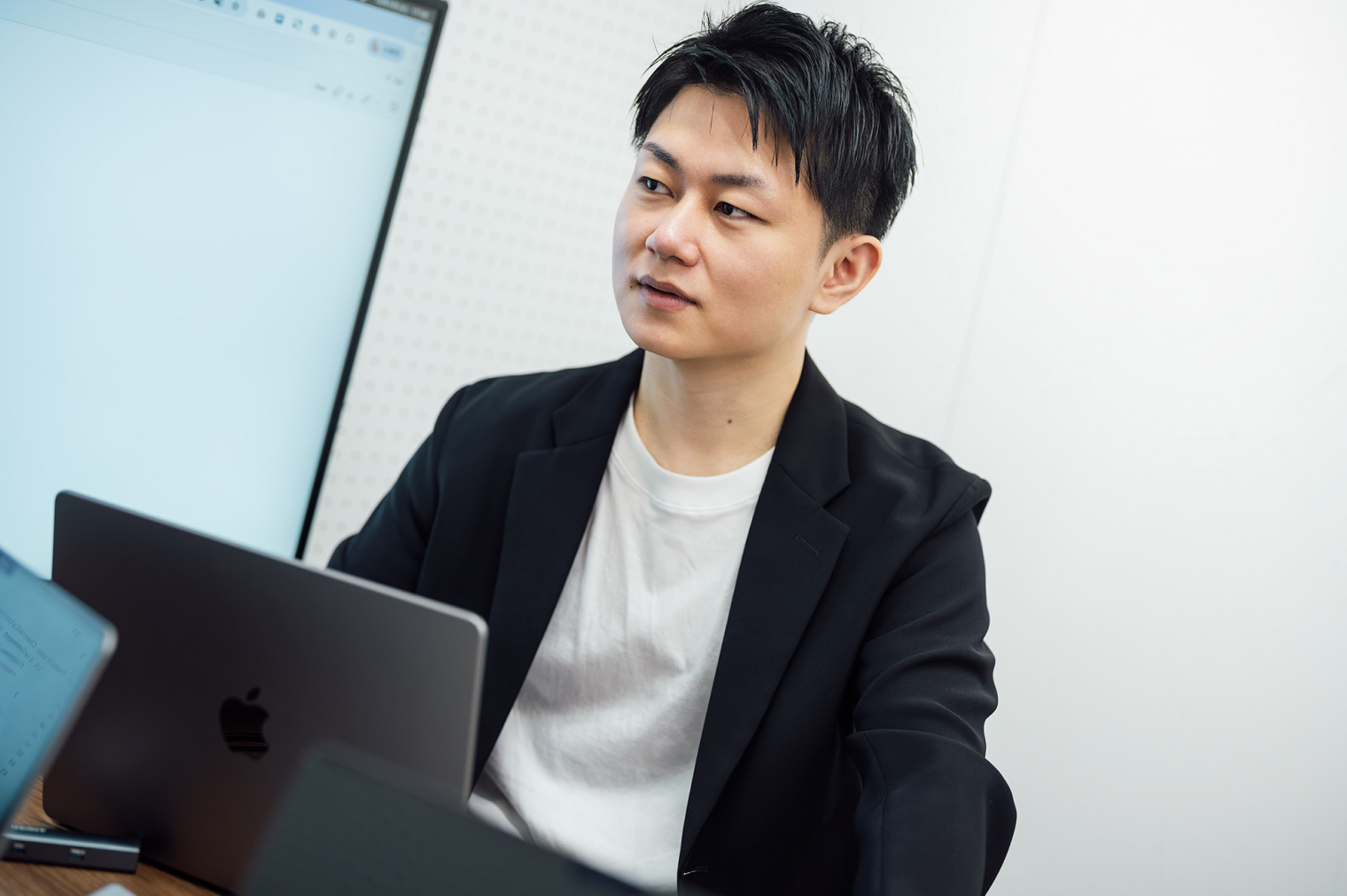 1名の社員がノートパソコンを前に、他の社員に目線を配っている様子。