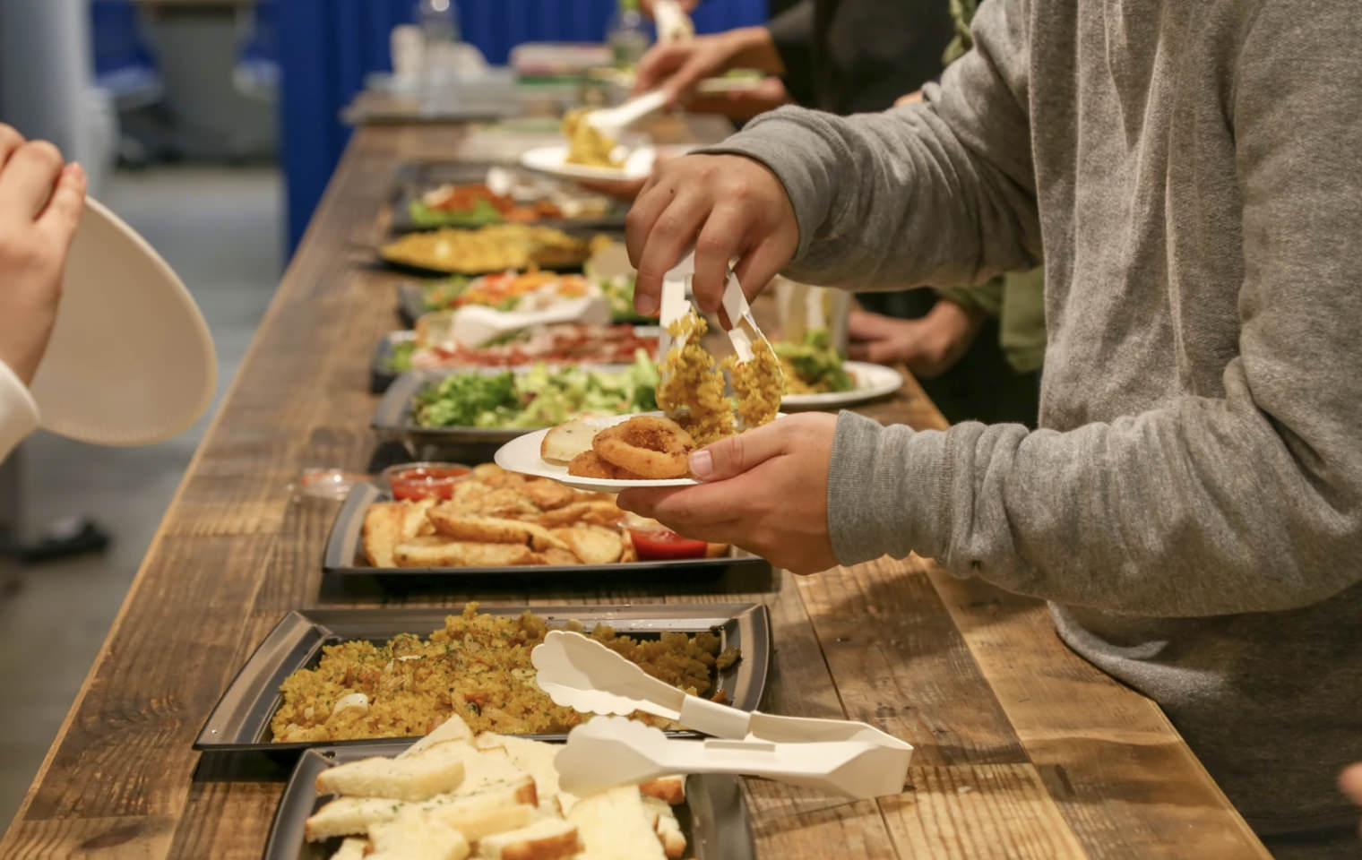 ウェルカムランチで社員がビュッフェ形式の料理を皿に取り分けている様子。