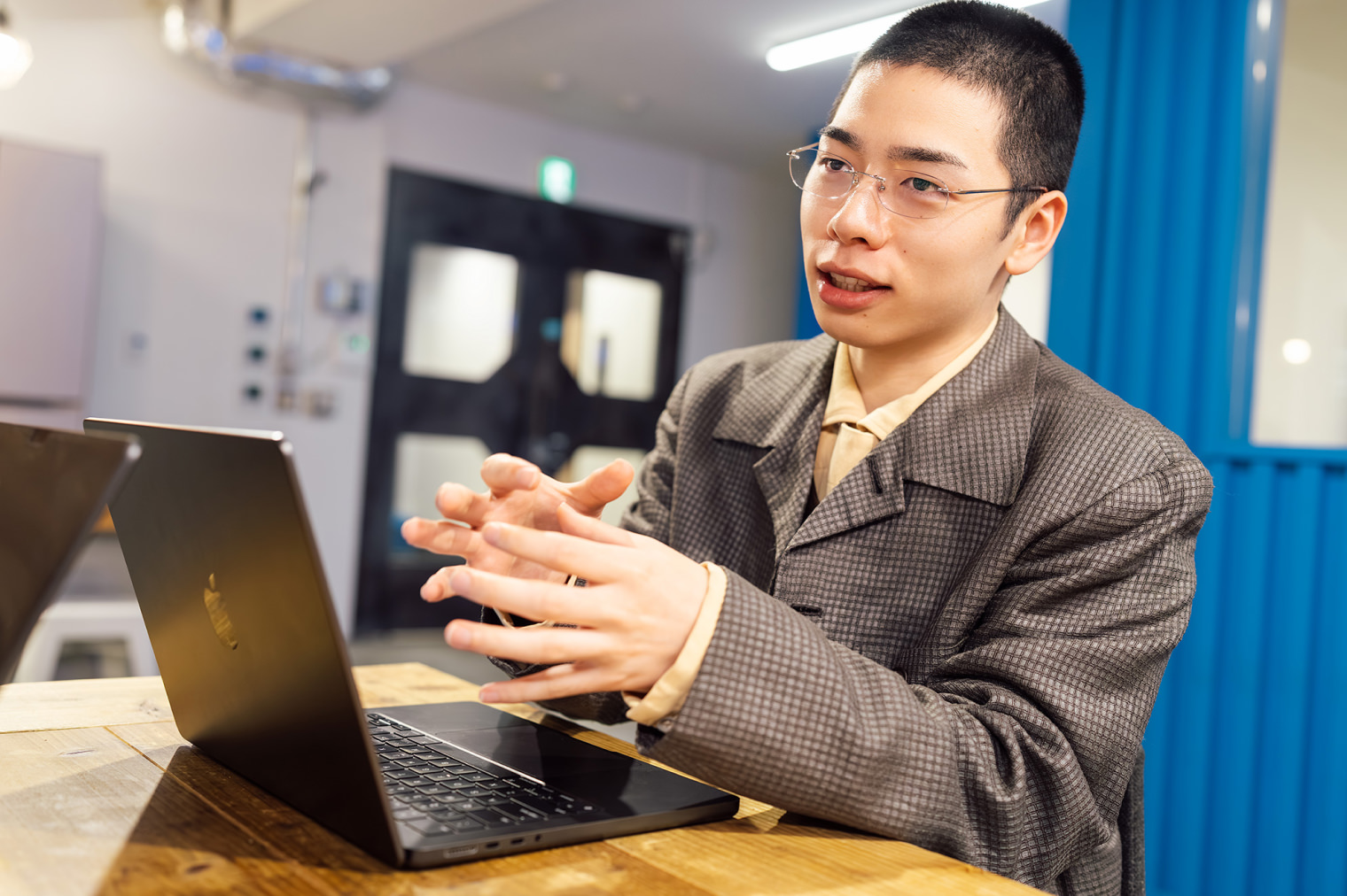 1名の社員がノートPCを前に、画面外の相手に話している様子。