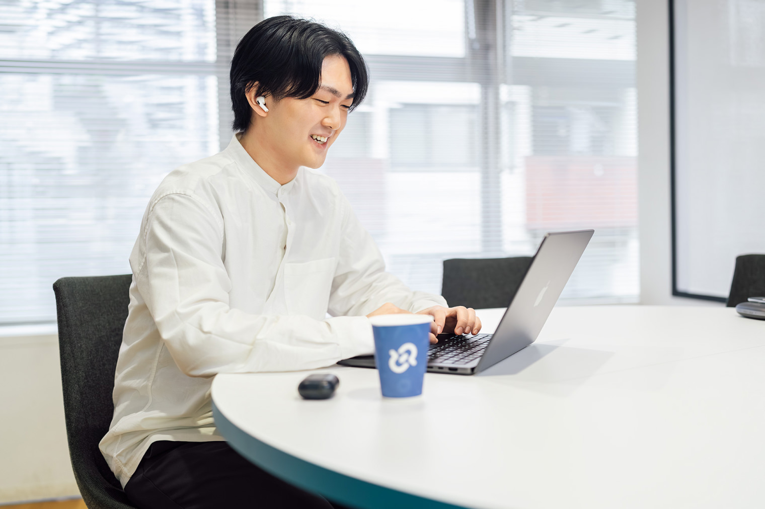 ノートPCを前に笑顔で話している社員。手前にはグッドパッチオリジナルの紙コップが置かれている。